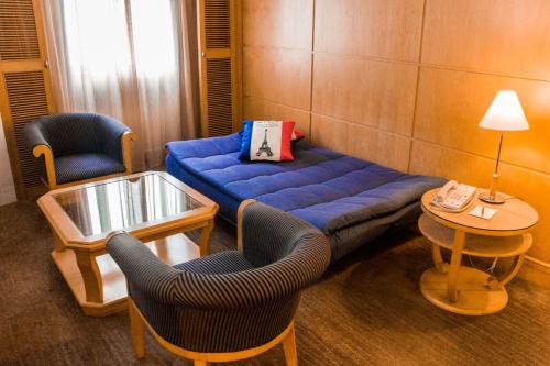 a living room with a blue couch and two chairs at Grand Park Wuxi in Wuxi