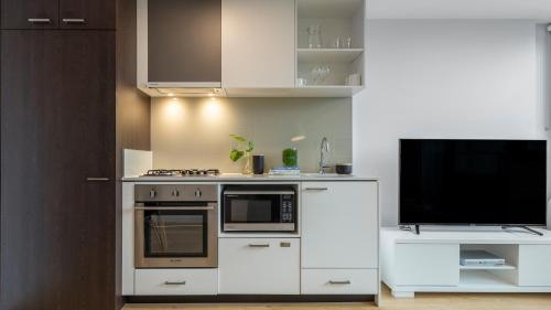 a kitchen with a stove and a tv at Oaks Melbourne Southbank Suites in Melbourne