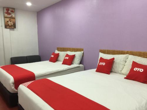 two beds in a room with red and white pillows at OYO 89671 Changlun Star Motel in Changlun