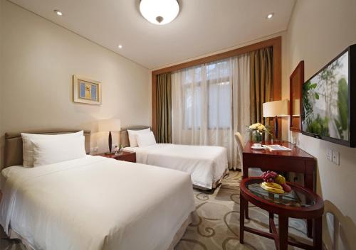 a hotel room with two beds and a table at City Hotel Xiamen-Free Welcome Fruits in Xiamen