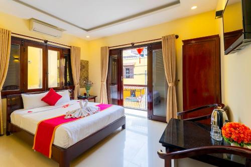 a bedroom with a bed and a desk and a window at Golden River Hotel in Hoi An