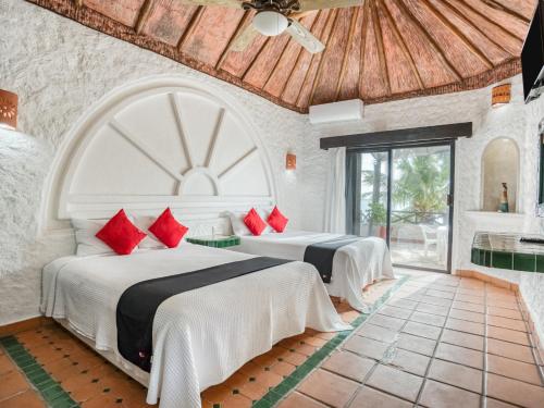 1 dormitorio con 2 camas y almohadas rojas en Capital O Mimi Del Mar, Playa del Carmen en Playa del Carmen