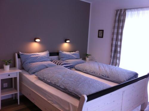 a bed with four pillows on it in a room at Haus Strandlaeufer in Dranske