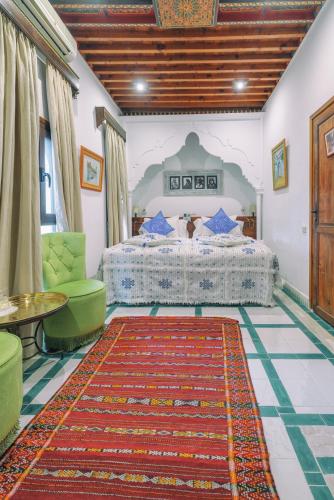 a bedroom with a bed and a green chair and a rug at Dar Baibou in Chefchaouen