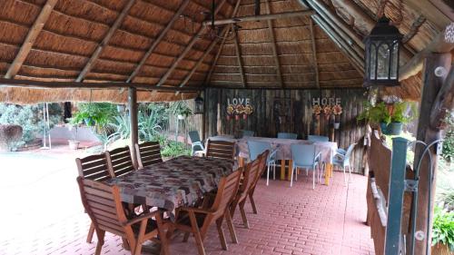 a dining room with a table and chairs under a roof at St Michelle Guest Lodge & Hydro Retreat in Alberton