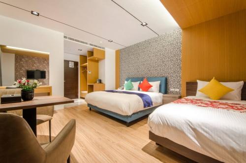 a hotel room with two beds and a desk at Mucun Hot Spring Resort in Jiaoxi