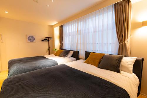 two beds in a hotel room with a window at belle lune hotel hakata Suite Room 1 in Fukuoka