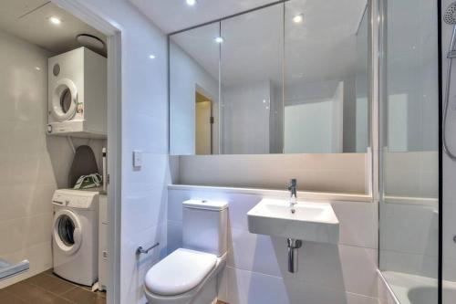 a bathroom with a toilet sink and a washing machine at Darwin Waterfront Luxury Apartment in Darwin