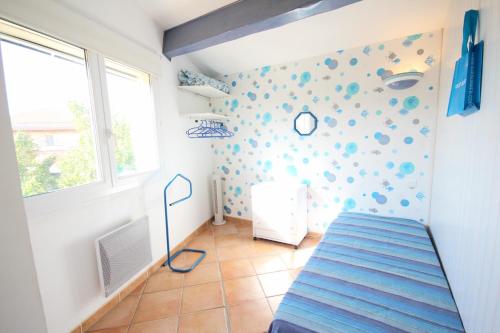 Cette chambre dispose d'un lit et d'un mur avec des points de polka. dans l'établissement 50m de la plage vue mer Très belle maison 3 chambres 5 couchages grand jardin parking voitures LXMURIER, à Portiragnes