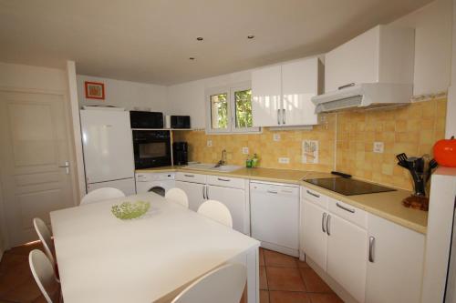 une cuisine avec une table blanche et des armoires blanches dans l'établissement 50m de la plage vue mer Très belle maison 3 chambres 5 couchages grand jardin parking voitures LXMURIER, à Portiragnes