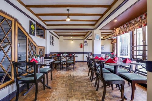 un restaurante con mesas y sillas con servilletas rojas en Summit Grace Boutique Hotel & Spa, en Darjeeling