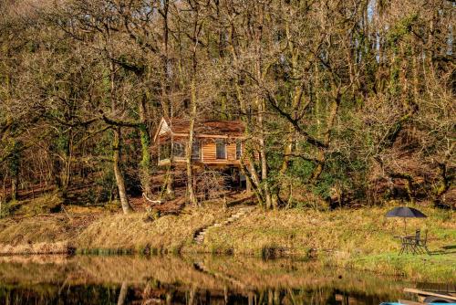 a person with an umbrella sitting in front of a house at Finest Retreats - The Tree House - Eco-Friendly, Back to Nature Experience in Germansweek