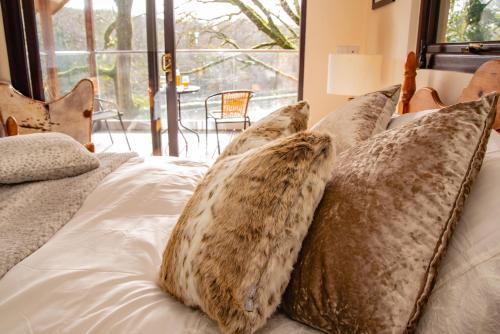 a bed with a bunch of pillows on it at Finest Retreats - The Tree House - Eco-Friendly, Back to Nature Experience in Germansweek