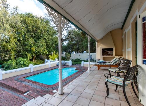 um pátio com uma piscina, uma mesa e cadeiras em Evergreen Lodge em Stellenbosch