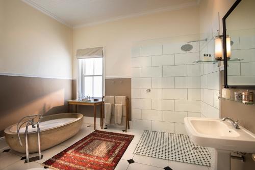 a bathroom with a tub and a sink at Kwandwe Uplands Homestead in Grahamstown