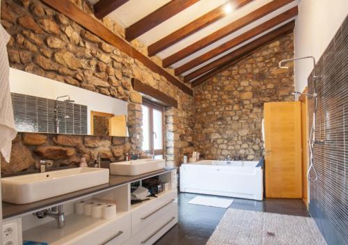 Baño con paredes de piedra, 2 lavabos y bañera en Excepcional chalet cerca de Cabárceno, en Pámanes