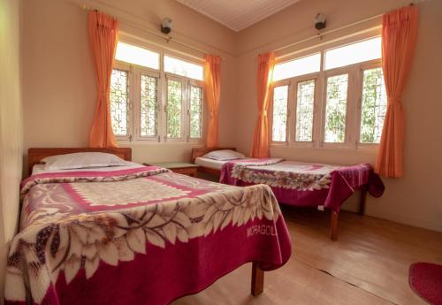 two beds in a room with windows at New Tourist Guest House in Pokhara