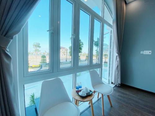a room with two white chairs and a large window at THE VILLA HIEU HY in Quy Nhon