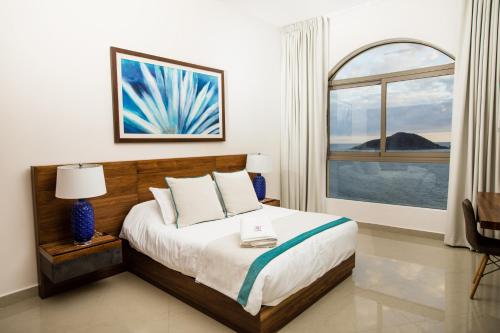 a bedroom with a bed and a large window at Petit Luxe Las Gavias Penthouse in Mazatlán