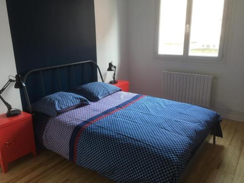 ein Bett mit blauer Decke in einem Schlafzimmer in der Unterkunft Le Coin du Pêcheur in Le Havre
