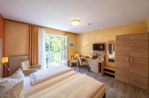 a hotel room with two beds and a television at Stadthotel Pfeffermühle in Gengenbach