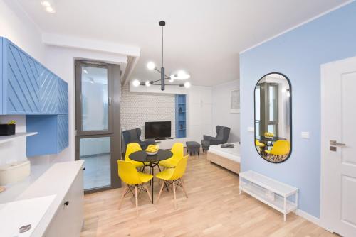 a kitchen and living room with yellow chairs and a table at YOURAPART Długie Ogrody in Gdańsk