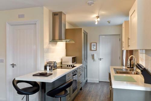 a kitchen with a counter and two stools in it at Swan Place Apartments By Viridian Apartments in Swindon