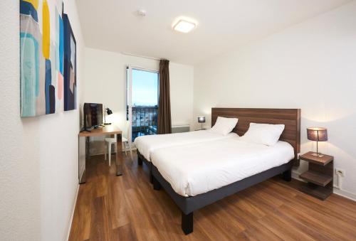 a bedroom with a large white bed and a window at Ténéo Apparthotel Talence in Talence