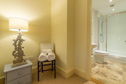 a bathroom with a toilet and a table with a lamp at Higham Place Lodge in Higham