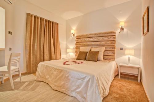a bedroom with a large bed and a chair at Prado Villas in Vilamoura