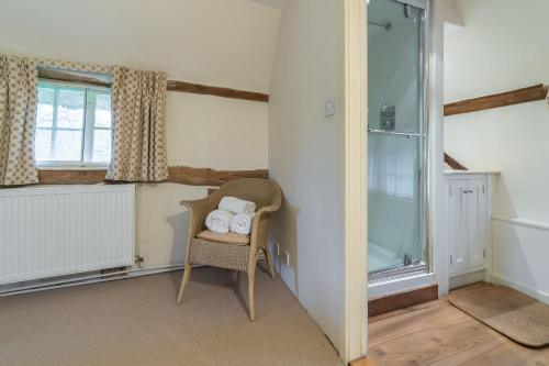 een kamer met een stoel, een douche en een raam bij The Gildhall in Higham