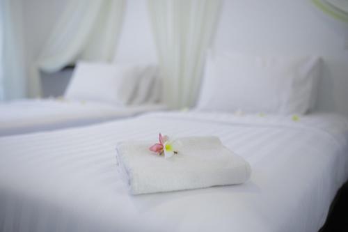 a white bed with a white towel with a flower on it at Aman Dan Laut in Perhentian Island