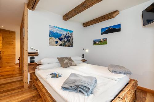 a bedroom with a bed with white sheets and wooden floors at B&B Sot l'Agner - Ospitalità Diffusa Conca Agordina in Taibon