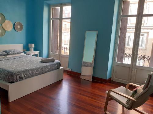 Schlafzimmer mit blauen Wänden, einem Bett und einem Stuhl in der Unterkunft Casa Centro in San Sebastián