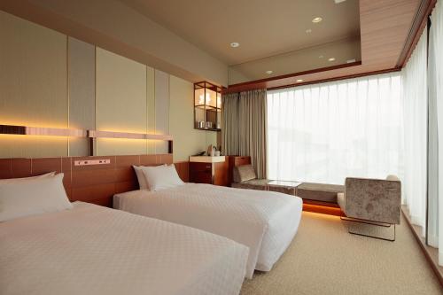 さいたま市にあるカンデオホテルズ大宮のベッド2台と窓が備わるホテルルームです。