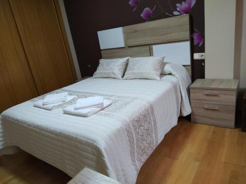 a bedroom with a white bed with two towels on it at Piso Tesa in Arévalo