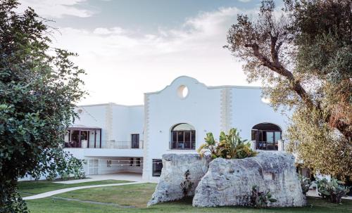 biały budynek z drzewami przed nim w obiekcie Acaya Golf Resort & Spa w mieście Acaya