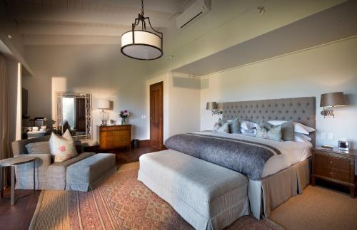 a large bedroom with a large bed and a chair at Kwandwe Fort House in Grahamstown