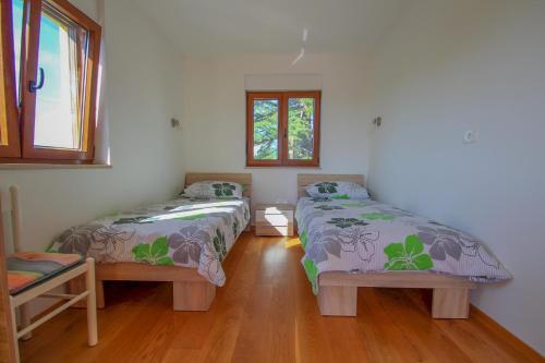 two beds in a room with two windows at Villa Agata in Dajla