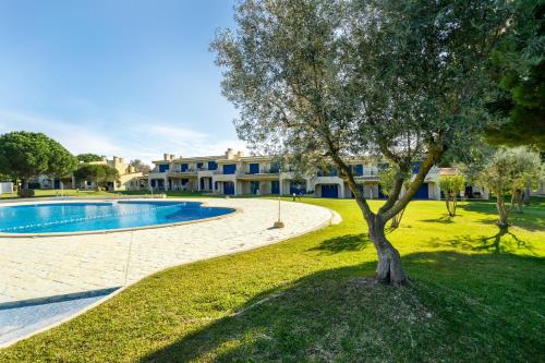 a tree in the grass next to a swimming pool at PARAISO DE ALVOR - A true paradise in an amazing nature place with direct access to the pool - Peace and relax - next to Alvor Village and the beach in Alvor