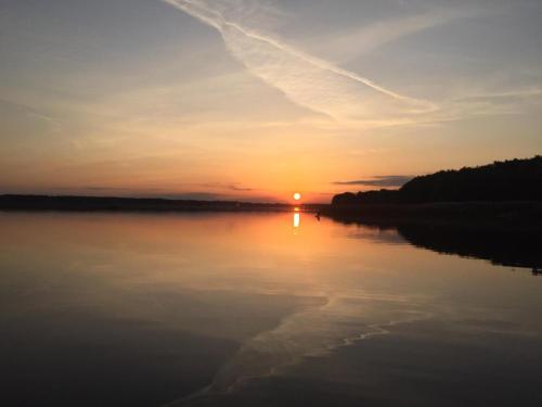 a sunset on a lake with the sun in the sky at Yacht Club Apartamenty in Radzyń