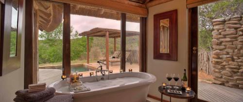 a large bath tub in a room with a large window at Kwandwe Great Fish River Lodge in Grahamstown