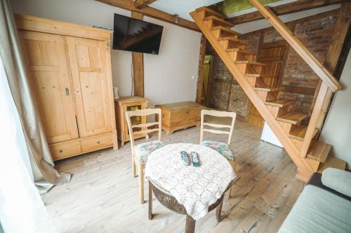 een woonkamer met een tafel, stoelen en een trap bij Pod Złotym Kasztanem in Duszniki Zdrój