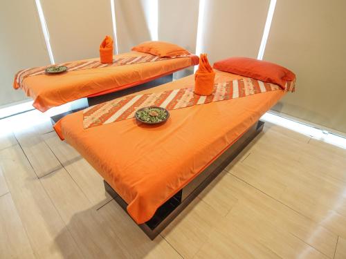 two beds in a room with orange comforters at HARRIS Hotel Pontianak in Pontianak