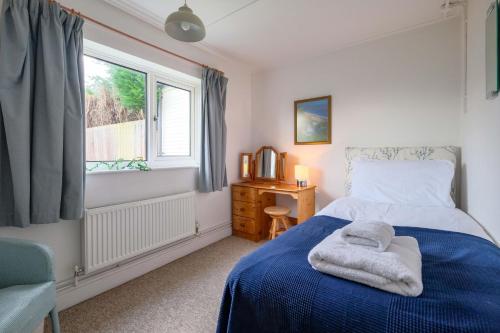 a bedroom with a blue bed and a window at Beaver Cottage in Aldeburgh