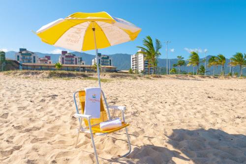 a chair and an umbrella on a beach at Hotel Costa Norte Massaguaçu in Caraguatatuba