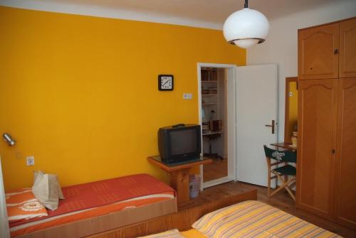 a yellow room with a bed and a television at Guesthouse 7even in Mostar