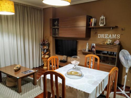 una sala da pranzo con tavolo, sedie e TV di Apartamento Dreams a Vigo