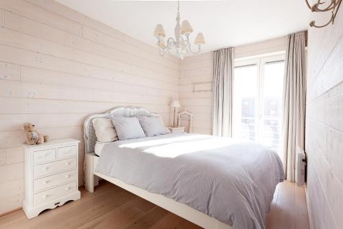 ニーウポールトにあるApartment Zonnehavenの白いベッドルーム(白いベッド1台、シャンデリア付)