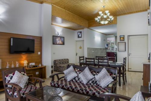 a living room with couches and a television and a table at Kasauli Edge Apt with Balcony in Kasauli